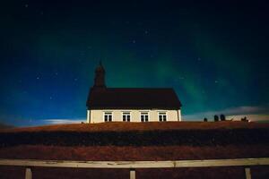 Islandia - marzo 20, 2023 -strandarkirkja protestante Iglesia con tumba a noche con claro cielo y Aurora boreal. famoso Aurora borealis del Norte luces persiguiendo caza excursión ubicaciones foto