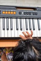 Asian cute girl playing the synthesizer or piano. Cute little kid learning how to play piano. Child's hands on the keyboard indoor. photo