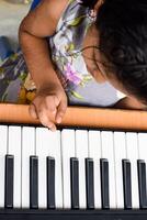 Asian cute girl playing the synthesizer or piano. Cute little kid learning how to play piano. Child's hands on the keyboard indoor. photo