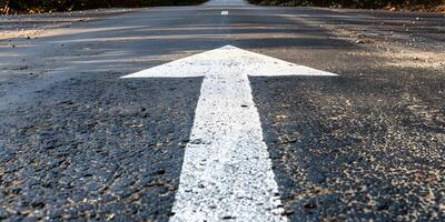 An asphalt road stretches into the distance with a painted white arrow pointing forward, symbolizing motivation, progress photo