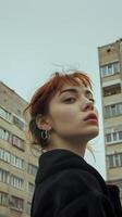 A woman with red hair and green eyes stands in front of a building photo