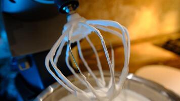 Beaten egg cream whites until frothy. Whipped egg whites for a meringue. Red stationary mixer, food processor take out beater photo