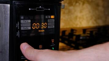 man using modern multi cooker in kitchen. choosing program photo