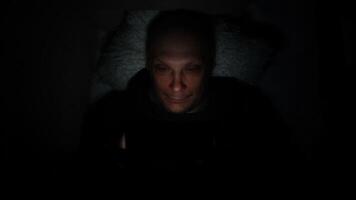 Lonely caucasian middle ages man lie on bed in bedroom and using phone at night. Face illuminated from smartphone display. Surfing social network before sleep photo