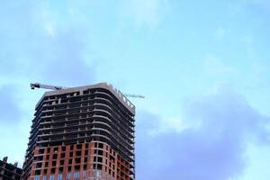 Low angle view of modern office building by construction site against sky in city photo