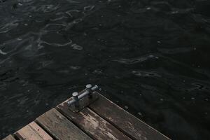 A metal mooring bollard and its shadow on an old wooden dock pier. Background. View from above. photo