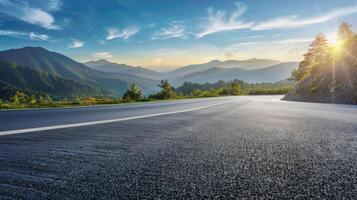 An empty asphalt road winding through a mountainous landscape with a blue sky and white clouds photo