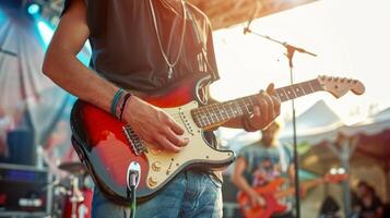Hipster man wearing a blank black t-shirt mockup while playing guitar at a music festival photo