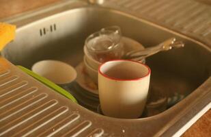 Stack of dirty dishes with food leftovers in the kitchen sink. Unwashed dishes photo