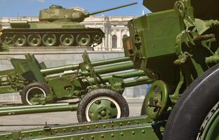 Photo of three guns of the Soviet Union of the Second World War against the background of the green tank T-34