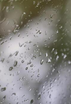 una foto de gotas de lluvia en el cristal de la ventana con una vista borrosa de los árboles verdes florecientes. imagen abstracta que muestra las condiciones meteorológicas nubladas y lluviosas