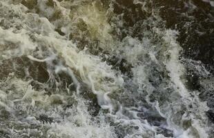 Waves of water of the river and the sea meet each other during high tide and low tide. Deep blue stormy sea water surface with white foam and waves pattern, background photo