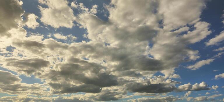 A blue cloudy sky with many small clouds blocking the sun photo