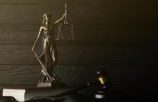 The Statue of Justice - lady justice or justitia the Roman goddess of Justice. Statue on brown book with judge gavel. Concept of judicial trial, courtroom process and lawyers work photo