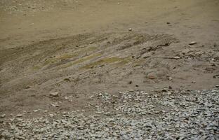A dirty road with traces of a car driving through the damp ground photo