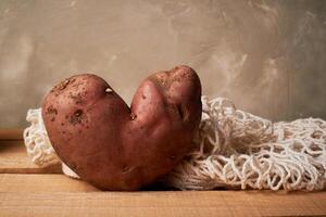 Ugly food, potatoes in the shape of a heart.Natural and simple farm products. Bag string bag, refusal of plastic. photo