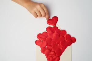 Kraft the envelope with red hearts on a white background.Congratulations on Valentine's Day. Hearts fly out of the envelope. Hands, top view. photo