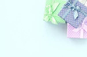 Pile of a small colored gift boxes with ribbons lies on a violet background. Minimalism flat lay top view photo