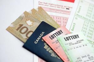 Lottery tickets lies with canadian dollars on gambling sheets with numbers for marking to play lottery photo