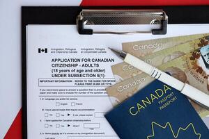 Application for Canadian citizenship for adults on table with pen, passport and dollar bills photo