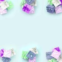Piles of a small colored gift boxes with ribbons lies on a violet background. Minimalism flat lay top view pattern photo