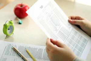 Female student hands testing in exercise and hold exam paper sheet with pencil at school test room photo