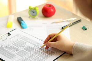 Female student hands testing in exercise and taking fill in exam paper sheet with pencil at school test photo