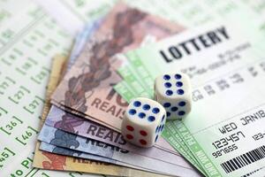 Green lottery tickets and brazilian reals money bills on blank with numbers for playing lottery photo