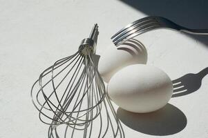 Egg with shadow from the fork. Minimalism. Cooking pastries, omelets. Easy. Whisk for whipping. Macro photo