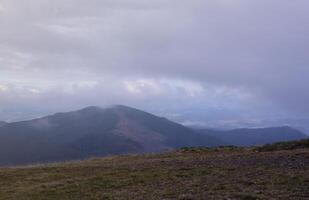 Morning view from the Dragobrat mountain peaks in Carpathian mountains, Ukraine. Cloudy and foggy landscape around Drahobrat Peaks photo