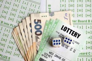 Green lottery tickets and ukrainian money bills on blank with numbers for playing lottery photo