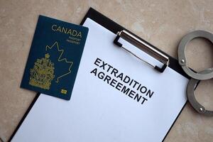 Passport of Canada and Extradition Agreement with handcuffs on table photo