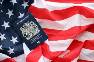 Blue British passport on United States national flag background close up photo