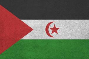 Western Sahara flag depicted in bright paint colors on old relief plastering wall. Textured banner on rough background photo
