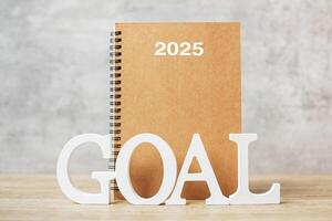 2025 Happy New Year with notebook and wooden number. goal, countdown, Resolution, Plan, Action and Mission Concept photo