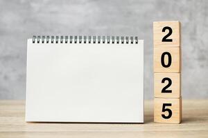 2025 Happy New Year with blank notebook and wooden number. countdown, Resolution, Goals, Plan, Action and Mission Concept photo