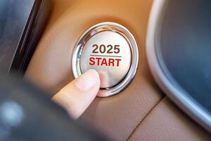 Finger press a car ignition button with 2025 START text inside automobile. New Year New You, forecast, resolution, motivation, change, goal, vision, innovation and planning concept photo