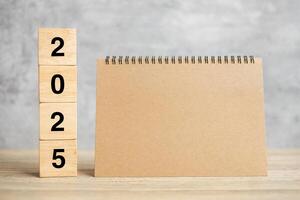 2025 Happy New Year with blank notebook and wooden number. countdown, Resolution, Goals, Plan, Action and Mission Concept photo
