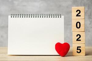 2025 cubes with red heart shape and empty notebook on table for your text. New Year, Resolution, Goal, plan, health, Love and Happy Valentine day concept photo