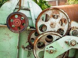 the gears on the machine are rusting and the green color of the paint is fading photo