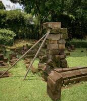 piles of ancient temple stones arranged and supported by wood as a restoration experiment photo