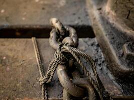 the chain is black because it is covered in drying used oil with small strands of rope tying it photo