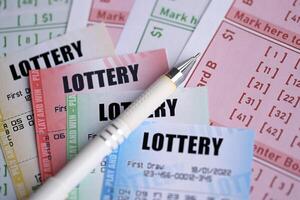 Lottery tickets of different colors and pen on blank bills with numbers for playing lottery photo