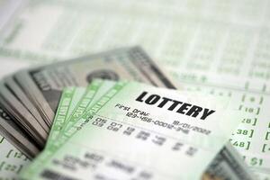 Green lottery tickets and US money bills on blank with numbers for playing lottery photo
