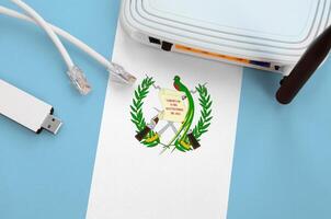Guatemala flag depicted on table with internet rj45 cable, wireless usb wifi adapter and router. Internet connection concept photo