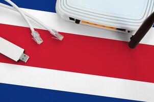 Costa Rica flag depicted on table with internet rj45 cable, wireless usb wifi adapter and router. Internet connection concept photo