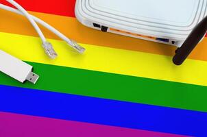 LGBT community flag depicted on table with internet rj45 cable, wireless usb wifi adapter and router. Internet connection concept photo