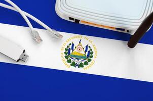 El Salvador flag depicted on table with internet rj45 cable, wireless usb wifi adapter and router. Internet connection concept photo