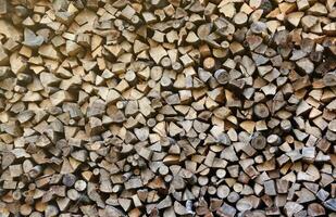 Firewood stacked near the wooden wall of old hut. Many chopped logs of firewood photo