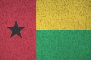 Guinea Bissau flag depicted in bright paint colors on old relief plastering wall. Textured banner on rough background photo